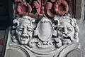 Deux visages encadrant un blason