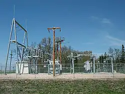 Une image d'une station de transformation non dissimulée à Warren, Minnesota, avec de nombreuses parties métalliques clôturées dans un champ ouvert.