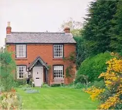 une maison de campagne en briques devant un grand jardin