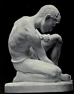 Une sculpture en marbre d'un garçon jouant aux billes