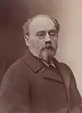 Photo noir et blanc d'un homme en buste, veste sombre, lorgnons, front dégarni et barbiche poivre et sel.
