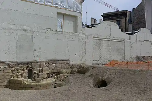 Base d'une tour de l'enceinte de Philippe Auguste, mise au jour lors des fouilles archéologiques dans l'Institut de France en 2015, avant la réalisation d'un nouveau bâtiment. L'enceinte marque la frontière entre l'Institut de France et la Monnaie de Paris. On voit également l'entrée d'un égout construit par Louis Le Vau dans les anciens fossés de l'enceinte, lors de la construction du Collège des Quatre-Nations au XVIIe&nbsp;siècle.
