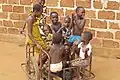 Enfants jouant avec une charrette à deux roues appelée pousse-pousse au Bénin