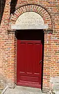 Porte latérale avec une imposte en pierre sculptée "Sainte-Eugénie".