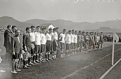 Photo en noir et blanc montrant des hommes alignés sur un terrain de football