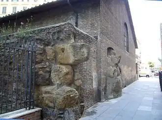 Photographie en couleurs de gros blocs de pierre encastrés dans le pignon d'une maison.