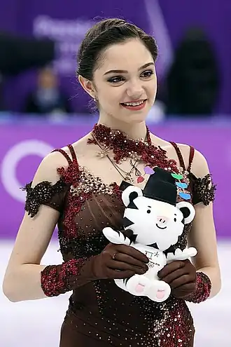 Une femme porte une robe rouge avec des fleurs, et tient une peluche de tigre blanc.