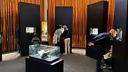 une salle d'exposition avec une vitrine au centre et des feuillets exposés autour
