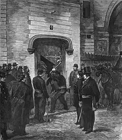 Un pompier armé d'une hache enfonce la porte du couvent sous l’œil attentif de l'autorité civile et des soldats, prêts à investir le lieu.