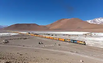Train vide près de l'établissement de Cebollar, en bordure du désert salé d'Acostan&nbsp;(en). Ce train est utilisé pour le transport de minerai d'argent en vrac entre la mine de San Cristóbal et Mejillones. Juillet 2013.