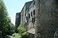 Façade entre deux tours. Les fenêtres ne sont pas alignées, à hauteurs variable alternant des fenêtre à meneau murées et des fenêtres plus récentes à volets mi-clos.
