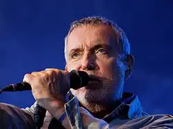 Homme au cheveux gris avec un microphone.