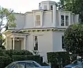 Un agencement similaire du rez-de-chaussée en maçonnerie et du deuxième étage à ossature bois, mais construit dans un style décoratif typique de San Francisco. Feusier Octagon House, San Francisco, California (construite en 1857).