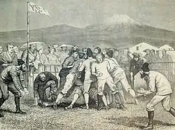 Gravure d'une partie de rubgy. Des hommes en costumes moulants sont regroupés ; le mont Fuji est visible au loin.