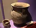 Un grand pot de rangement avec des décorations marquées par un cordon et des anses pour des sangles.