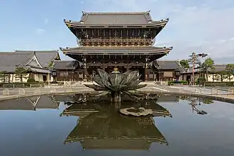 Porche d'entrée et Kaisan-dō du temple Higashi-Honganji, vu depuis l'extérieur avec une réflexion miroir dans l'eau d'une fontaine.