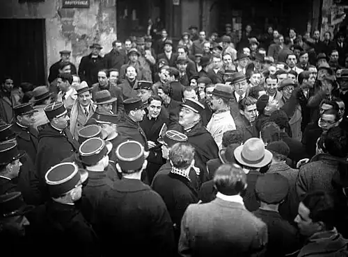 François Mitterrand (au centre, portant des livres) photographié durant la dispersion de cette même manifestation par la police.