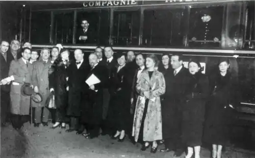 Photographie en noir et blanc d'une vingtaine de personnes posant lors d'une soirée.