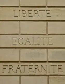 Devise française « liberté, égalité, fraternité » gravée sur un mur.