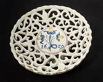 Coupe à pied (environ 7 cm de haut, 20 cm de diamètre), en faïence ajourée à glaçure au dioxyde d'étain en forme de vigne, produite en 1629 dans l'ouest de la Slovaquie/Moravie (peut-être à Sobotište), l'une des plus anciennes œuvres connues des Haban (de).