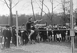 Photographie en noir et blanc d'un homme sautant au-dessus d'une barre