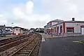Intérieur de la gare avec le bâtiment voyageurs et le quai central et son abri.