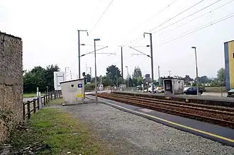 Gare de Landaul-Mendon : quais et les deux abris de la halte à accès libre, parking et le passage à niveau en bout de quais vers Vannes.