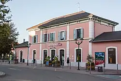 Photographie en couleurs d'un bâtiment de gare à la façade rose