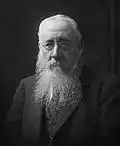 Photo noir et blanc. Vieil homme, longue barbe blanche, costume sombre.