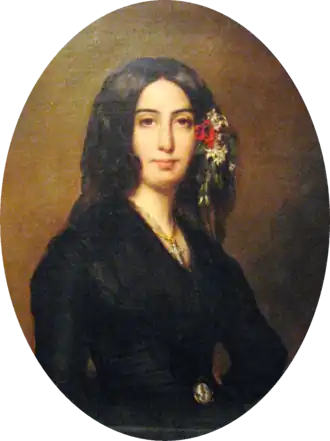 Portrait ovale d'une femme en buste vêtue de noir, les yeux noirs, des cheveux bruns encadrant le visage et mêlés de fleurs