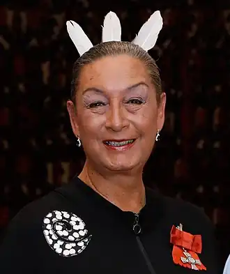 Dame âgée regardant la caméra avec du maquillage et trois plumes sur la tête