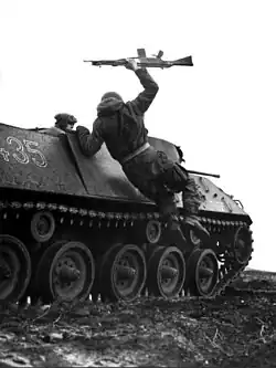 Photo noir et blanc d'un soldat sautant d'un véhicule blindé en tenant un fusil d'assaut dans la main.