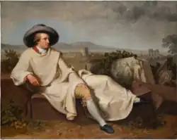 à gauche, homme drapé dans un long manteau clair, portant un large chapeau rond, se reposant étendu sur le sol dans la campagne romaine