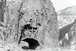 Photographie en noir et blanc du tunnel, creusé dans la roche.
