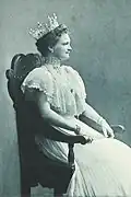 Photographie en noir et blanc d'une femme couronnée assise sur un trône.