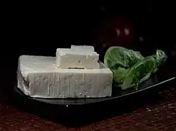 photographie d'une tranche d'un fromage blanc et de feuilles vertes