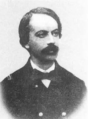 photo en noir et blanc d'homme moustachu, front dégarni, en uniforme de marine et nœud papillon.