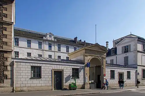 Photographie de l'entrée d'un hôpital, aux longs bâtiments depuis une rue.