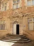 photo couleur d'une porte monumentale à pilastres et fronton orné d'un blason.