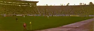 Vue panoramique de l’intérieur d’un stade de football, dans lequel un match se dispute devant des tribunes pleines.