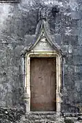 Porte de la maison du Sénéchal : un homme vêtu d'une robe courte et un autre vêtu d'une robe longue supportent la base des arcs, tandis qu'un ange couronne le frontispice