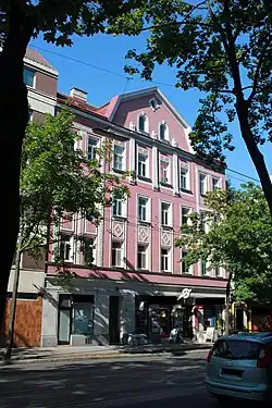 Photographie d'un immeuble ancien de quatre étages, avec une façade rose et blanche.