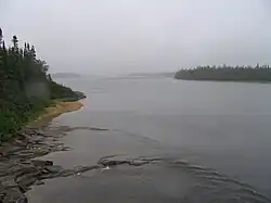 Photo de l'embouchure d'une rivière. Le ciel est gris en raison du brouillard.