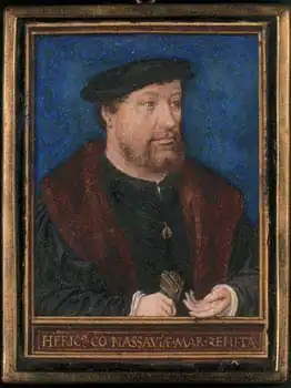 Portrait en buste, sur fond uni et bleu-foncé, d'un homme barbu, coiffé d'un béret, portant un costume sombre.