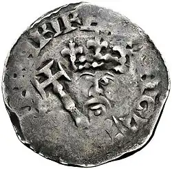 Pièce en argent très usée sur laquelle sont difficilement visibles une couronne, un sceptre et un visage barbu