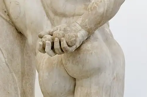 Main droite derrière le dos avec les pommes.