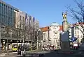 La place en novembre 2005, avec la bouche de métro, le centre commercial Karstadt et la statue centrale du couple de danseurs (Tanzendes Paar) sculpté par Joachim Schmettau&nbsp;(de) en 1985.