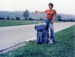 femme tendant le pouce dans l'herbe au bord d'une route
