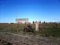 Panneau de gare avec le village derrière.
