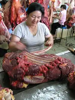 Une femme découpe une carcasse sanglante.
